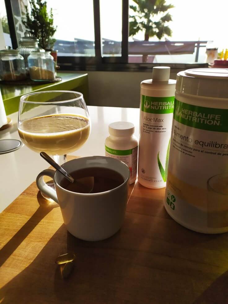 Colazione sana con prodotti Herbalife, un frullato e una tazza di tè, che mette in risalto la nutrizione e il benessere.