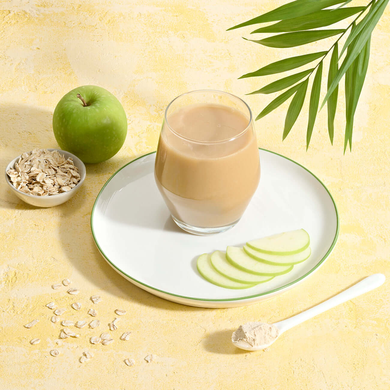 Herbalife Multi Fiber Drink in un bicchiere con fette di mela e avena su un piatto, per favorire l'assunzione di fibre e la digestione.