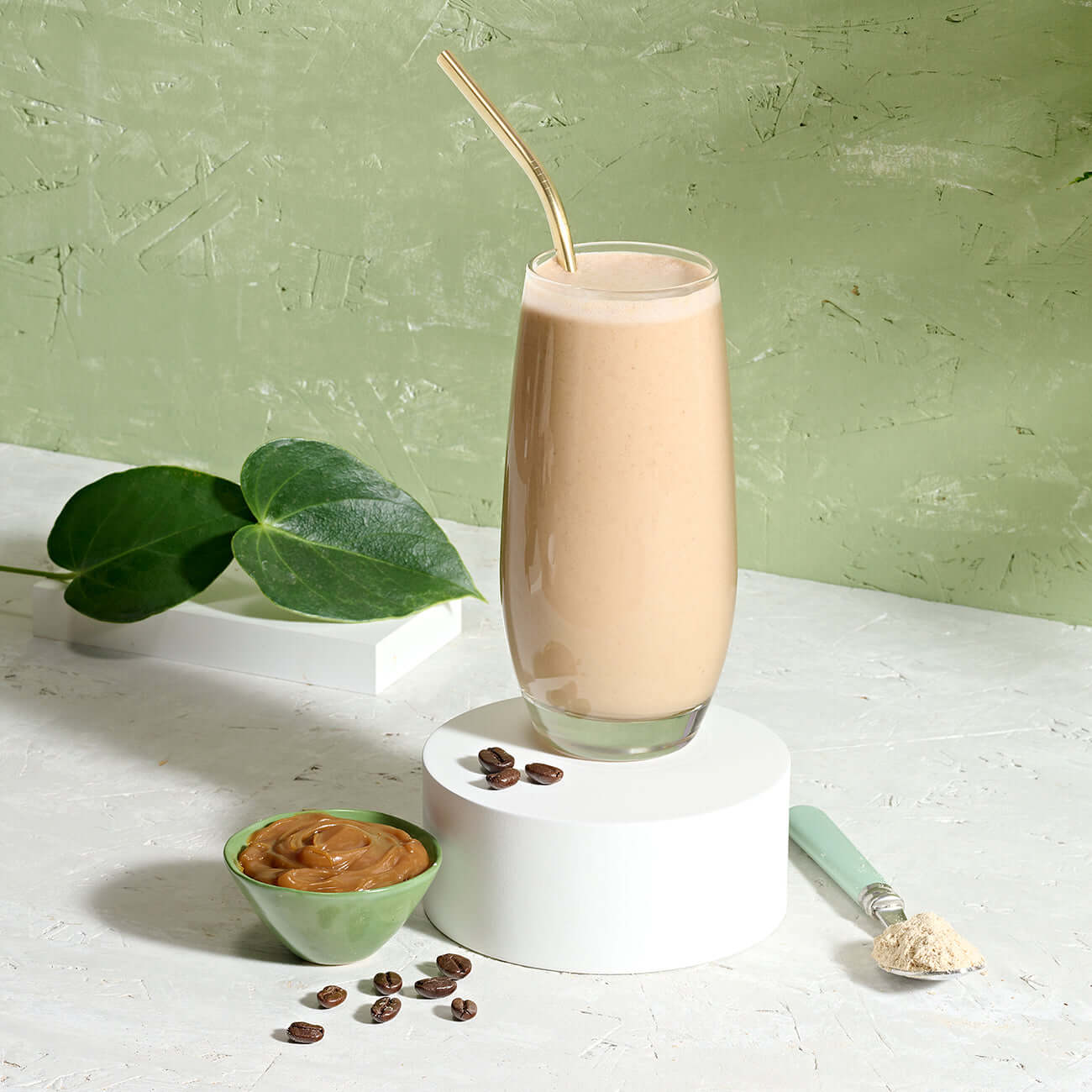 Herbalife Tri Blend Select protein shake in a glass with peanut butter and coffee beans on display.