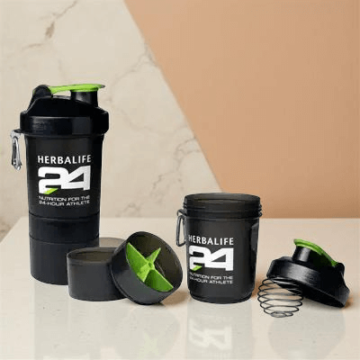 Shaker per proteine Herbalife 24 e contenitore per atleti, con accenti verdi su una superficie di marmo.