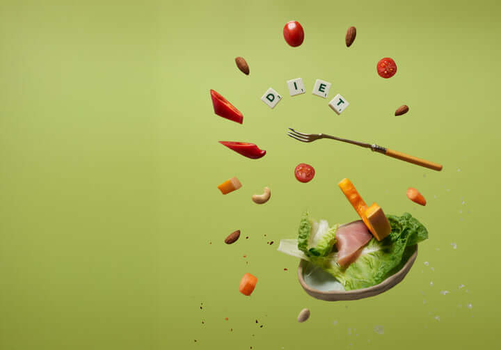 Concetto di dieta colorata con ingredienti freschi e la parola 'DIETA' visualizzata su uno sfondo verde vibrante.
